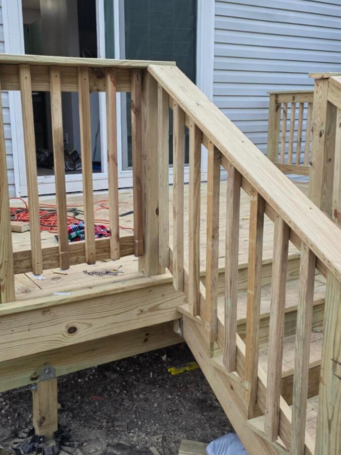 Finished deck—natural job-site view Completed wood deck and stair railing photographed at the job site